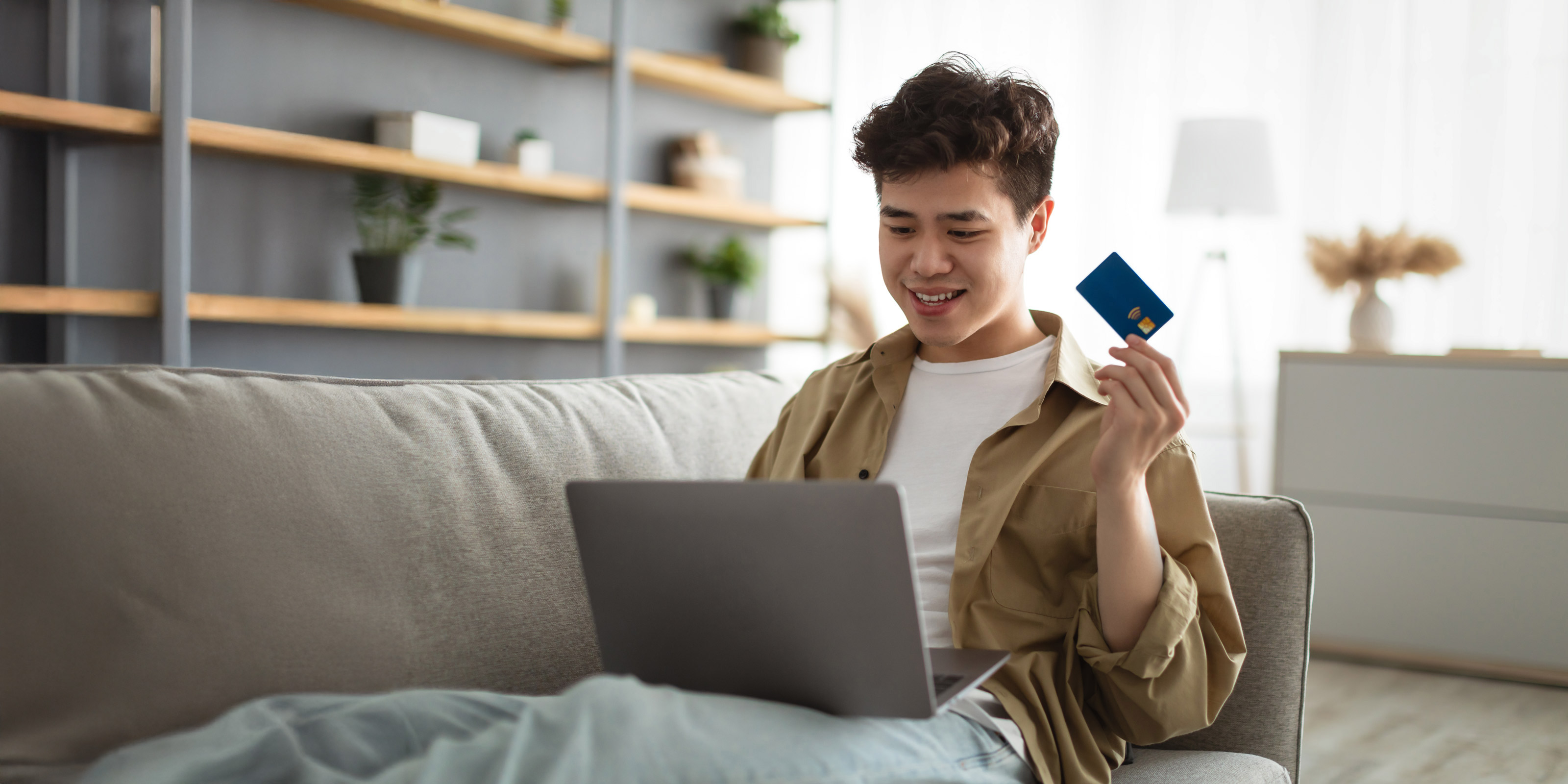 Man holding a card paying for product on his laptop